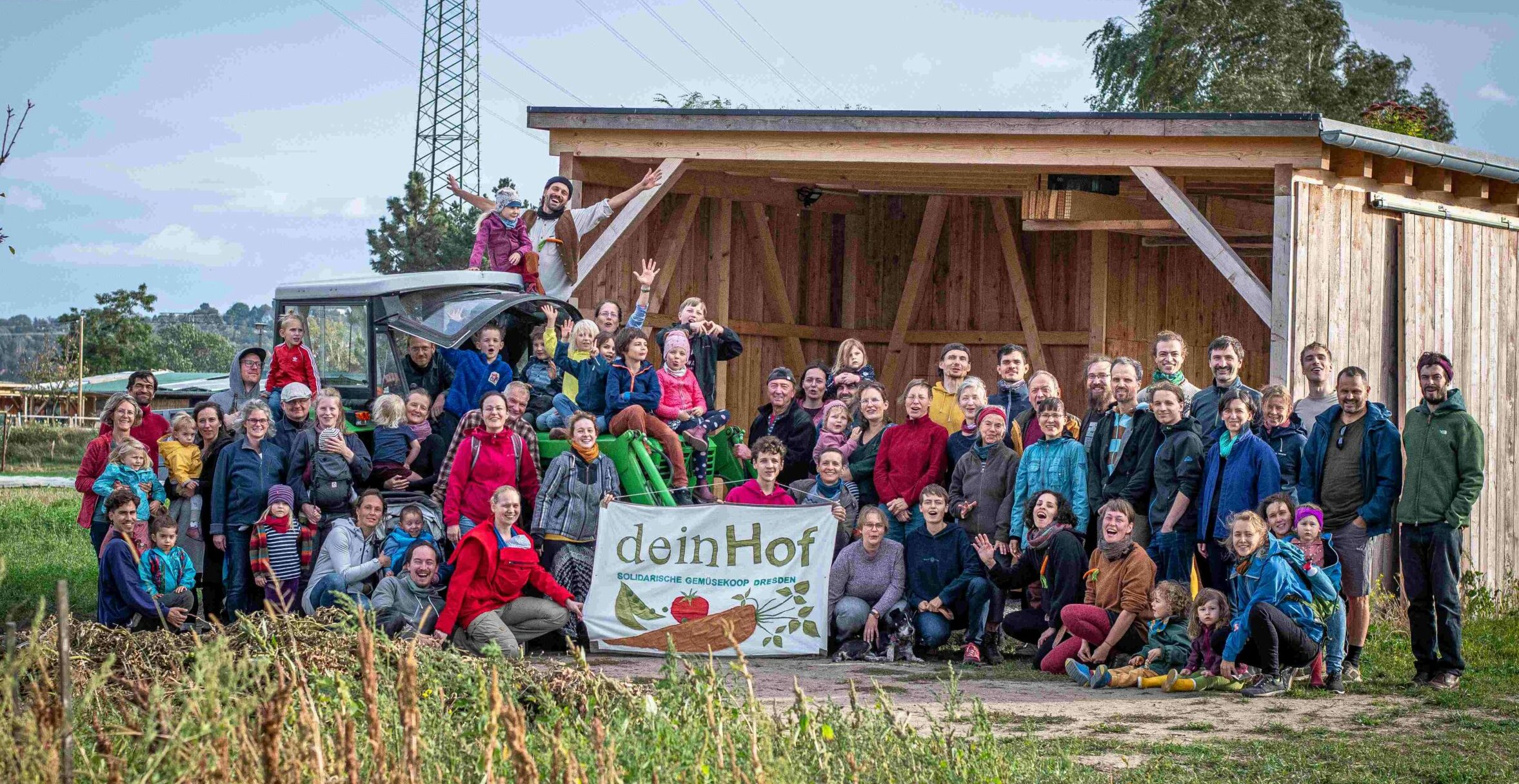 Ein Gruppenfoto der Solawi "dein Hof" mit vielen Kindern, Erwachsenen und einem Trecker.