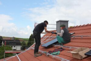 Bei Solocal Energy wird selbst Hand angelegt. Ein Foto mit zwei Menschen auf einem Dach, die eine Solaranlage installieren.